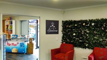 Una sala de estar con dos sillones rojos, una planta en la pared y un cartel que dice 'Yes to New Adventures'.