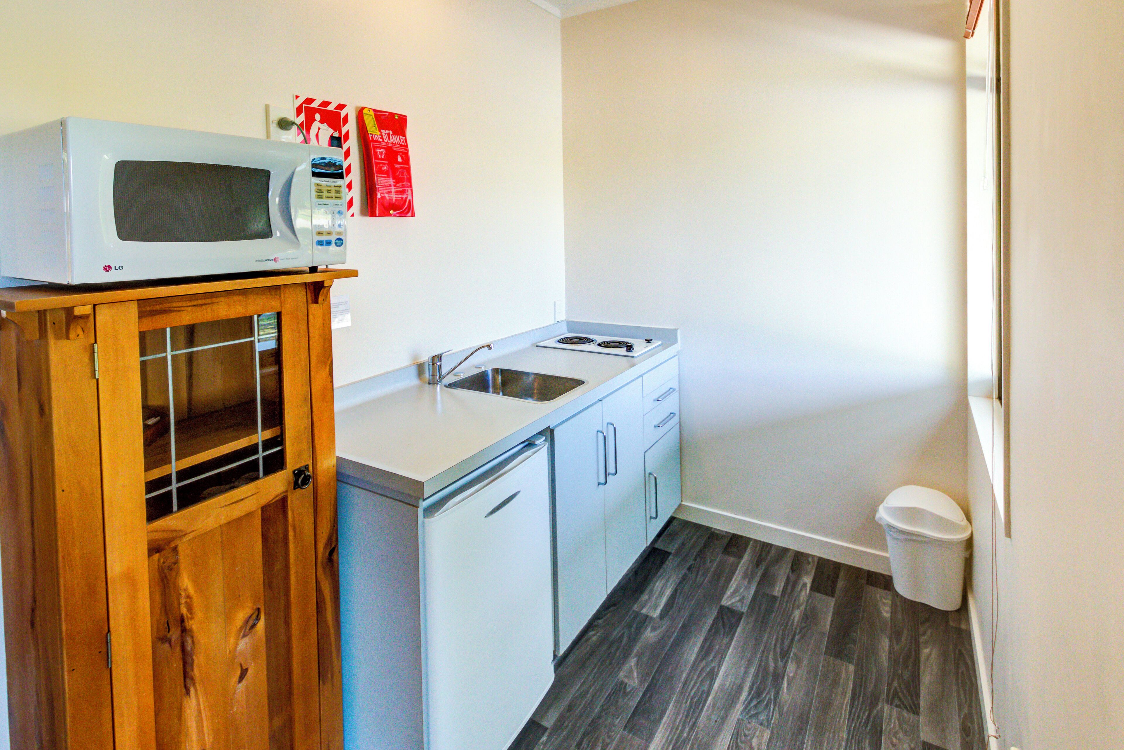 Una kitchenette compacta con microondas, lavamanos y refrigerador pequeño.