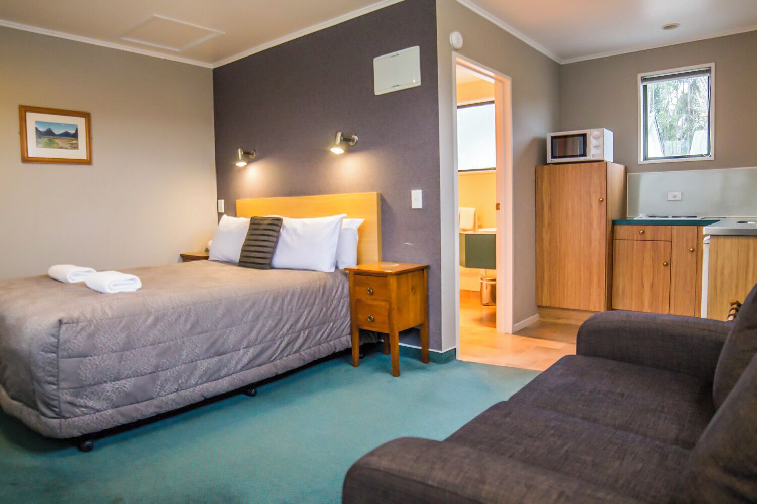 Une chambre à coucher avec un lit, une table de chevet et une vue sur la cuisine.