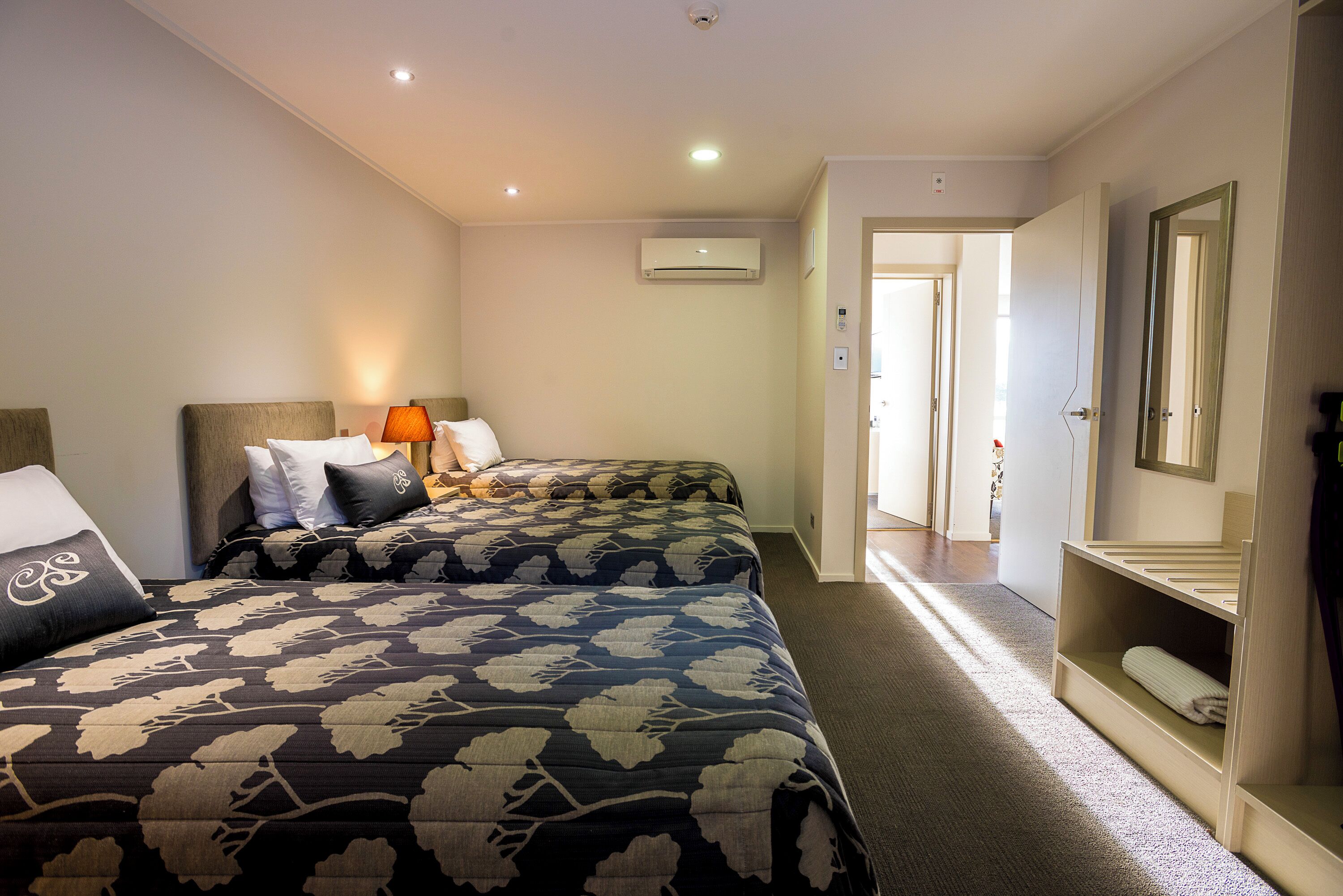 A hotel room with two beds, a walk-in closet, and a hallway leading to another room.
