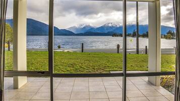 A view through a window of a lake with mountains in the background.