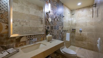 Une salle de bain avec un grand miroir, un lavabo, des toilettes et un espace douche.