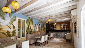 Un restaurante con un mural, vigas de madera en el techo e igualmente lámparas colgantes.