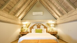 Un dormitorio con techo de madera, una cama con ropa blanca, dos lámparas de noche y una mesita de noche.
