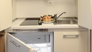 A compact kitchen with a built-in dishwasher, a sink, and a refrigerator with a freezer compartment. - Residence Lagrange (Turin)