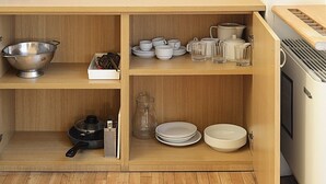 A compact kitchen with wooden shelves, a colander, a grater, a kettle, and various dishes. - Residence Lagrange (Turin)