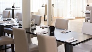 Un comedor moderno con una mesa grande, sillas y una araña.