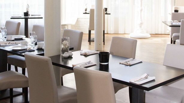 Un comedor moderno con una mesa grande, sillas y una araña.
