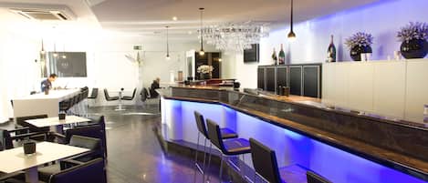 A modern bar area with a counter, bar stools, and a chandelier.
