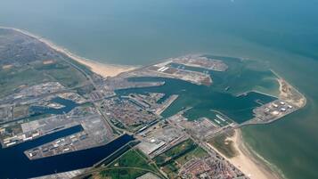 Vista aérea de uma área industrial costeira com várias docas, armazéns e uma praia.