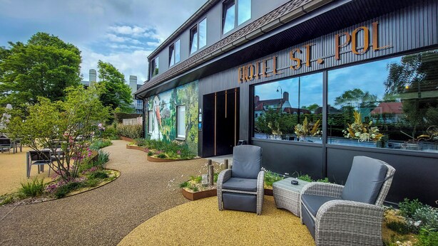 A hotel exterior with a garden patio, outdoor seating, and a mural. - Auberge St. Pol (Knokke-Heist)