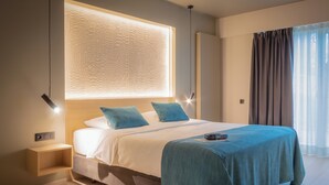 A modern hotel room with a large bed, a bedside table, a nightstand, a wall-mounted light, and a window with curtains. - Auberge St. Pol (Knokke-Heist)