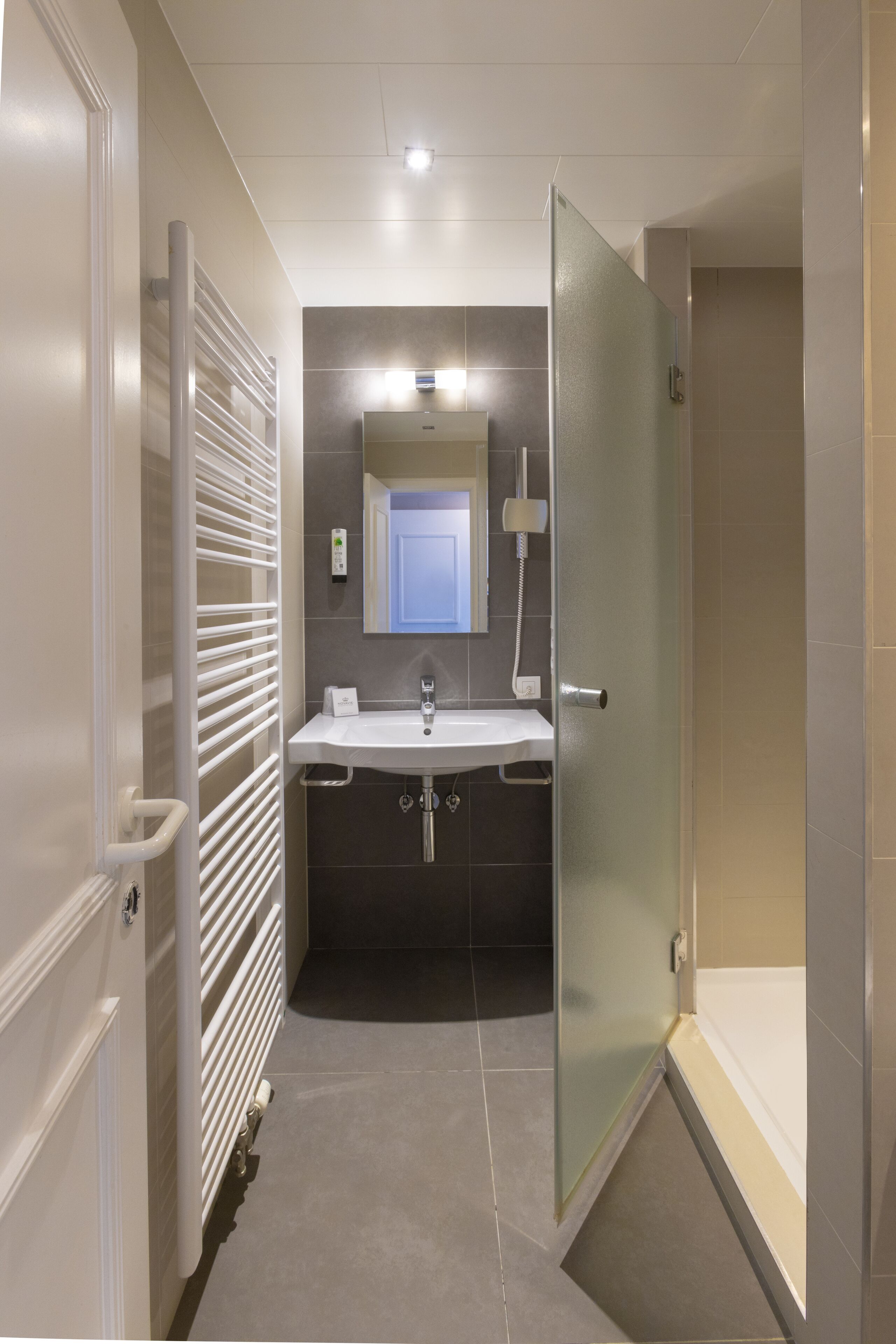 Un baño moderno con cabina de ducha de vidrio, un lavabo blanco y un espejo encima.