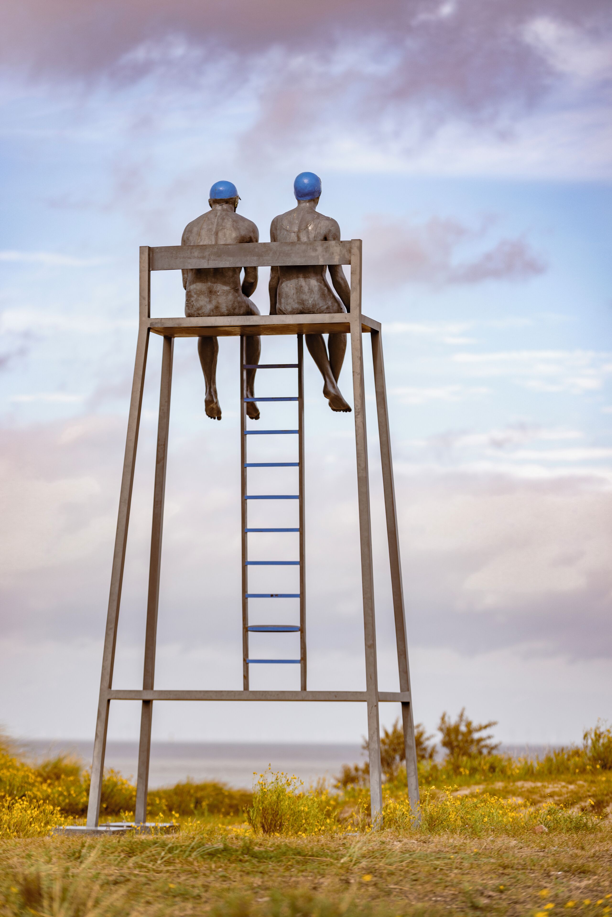Escultura de dos figuras sobre una escalera.