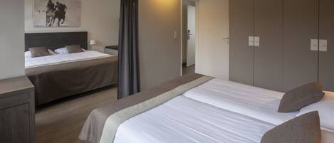 Habitación de hotel con dos camas, un armario, una mesita de noche y un cuadro en la pared.