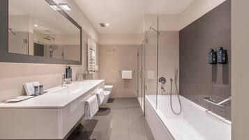 Un bagno moderno con uno specchio grande, una vasca da bagno, una doccia e il water.