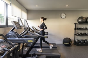 A gym with treadmills, a wall clock, and a shelf with exercise balls and kettlebells. - Move Hotels Venezia Nord (Mogliano Veneto)