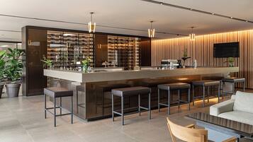 A modern bar area with a wine rack, bar stools, and a flat-screen TV.