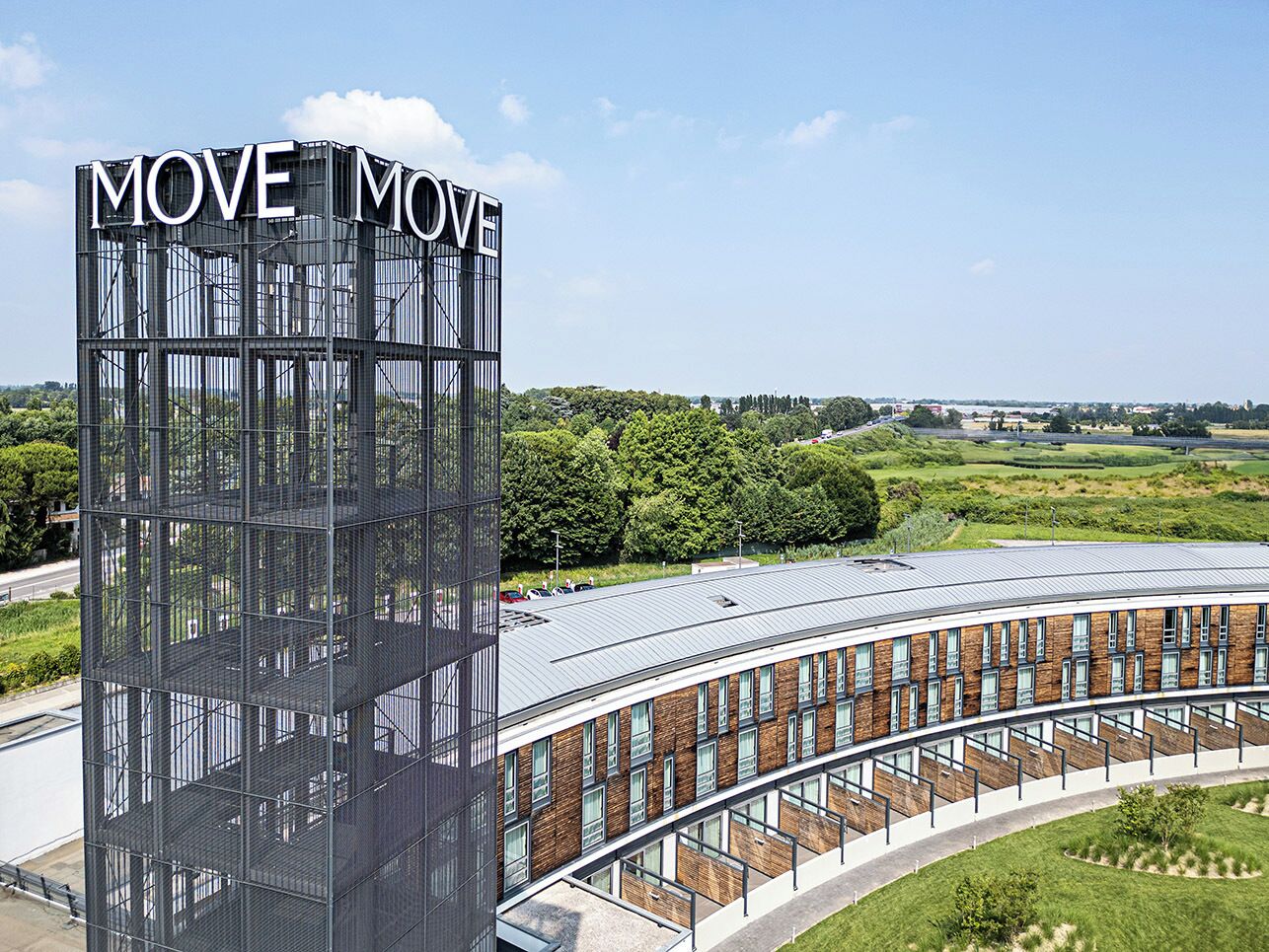 A modern building with a prominent 'MOVE MOVE' sign, featuring a curved structure with multiple windows and a metal framework.