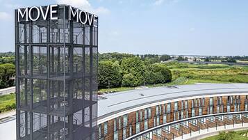 Ein modernes Gebäude mit einem auffälligen 'MOVE MOVE' Schild, das eine geschwungene Struktur mit zahlreichen Fenstern und einem Metallgerüst aufweist.