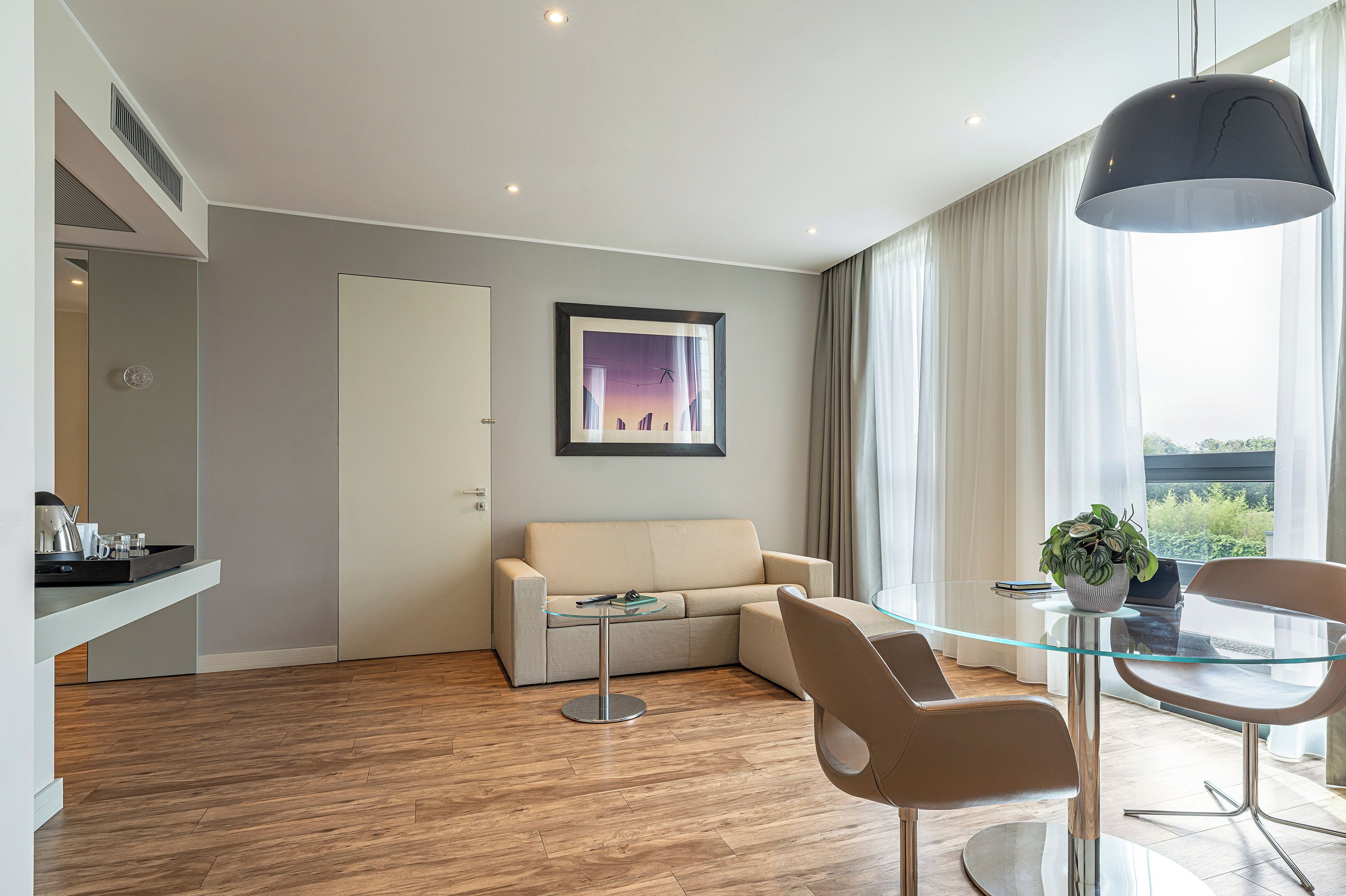 Ein modernes Wohnzimmer mit einem Glastisch, einer Couch, einem Couchtisch und einer Pendelleuchte.