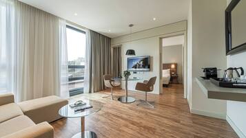 Ein modernes Hotelzimmer mit Wohnbereich, Essplatz und einer Küchenzeile.