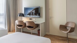 A hotel room with a bed, a desk with two chairs, a TV mounted on the wall, and a door. - Move Hotels Venezia Nord (Mogliano Veneto)