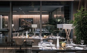 Un restaurante con una decoración moderna, que incluye divisiones de vidrio, mobiliario contemporáneo y vistas a la ciudad.