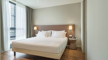 Habitación de hotel con una cama grande, dos lámparas de noche, una mesita de noche y vistas a la ciudad a través de la ventana.