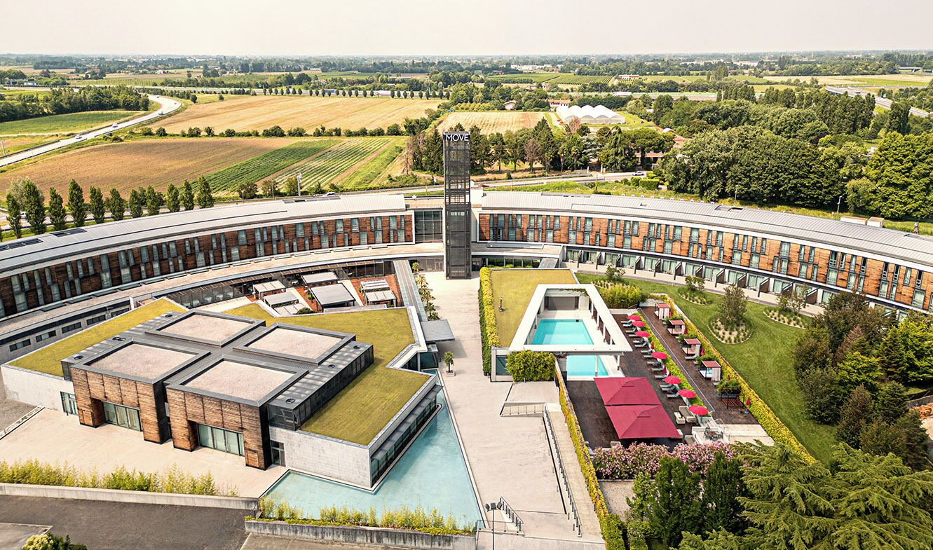 Un bâtiment moderne doté d’un toit incurvé, d’une tour centrale et d’une piscine.