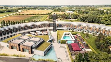 Un bâtiment moderne doté d’un toit incurvé, d’une tour centrale et d’une piscine.