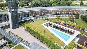 A modern building with a pool, a tall tower, and a well-maintained lawn. - Move Hotels Venezia Nord (Mogliano Veneto)