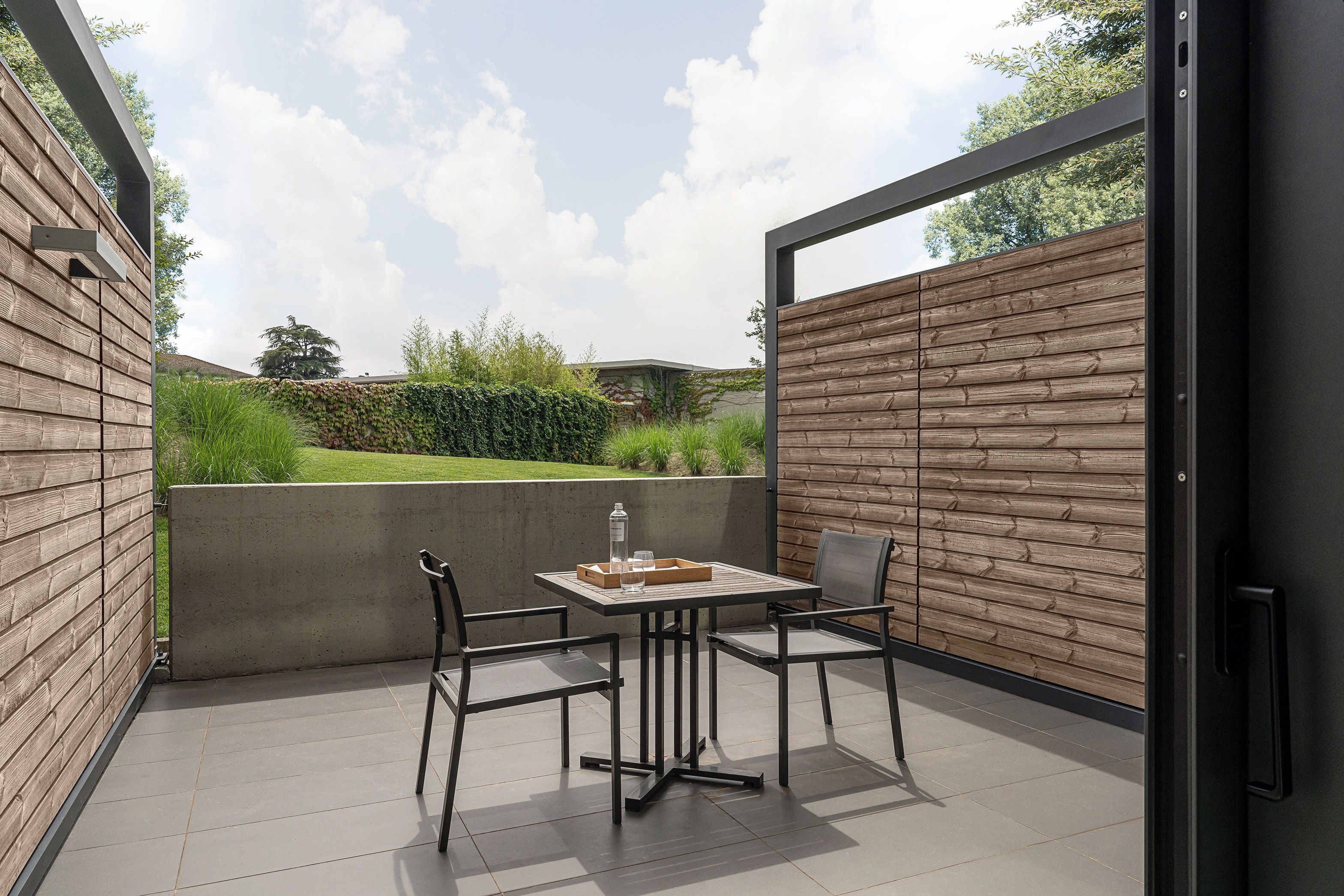 An outdoor patio with a table and chairs, a concrete wall, and a wooden fence.