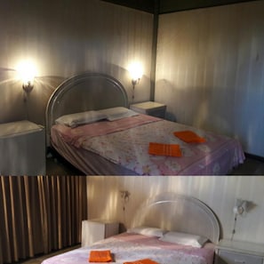 Un dormitorio con cama, mesitas de noche e iluminación en la pared.