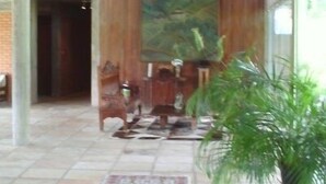 Een ruime lobby met een hoge plafond, een wand van houten panelen, een groot landschapsprent en een vloerkleed met een ruitpatroon.
