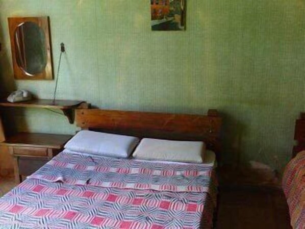 A simple room with a bed, a nightstand, a mirror, and a shelf with a phone and a picture frame. - Hotel Cupim Lazer (CRISTIANO OTONI)