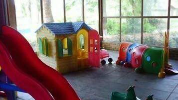 Kids can play and explore in this indoor play area featuring a slide, playhouse, and toy cars.