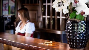 A wooden bar counter with a decorative vase of white flowers. - Seewinkel (Fuschl am See)