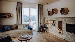 Un salon chaleureux avec un canapé, un fauteuil, une petite table et une cheminée.