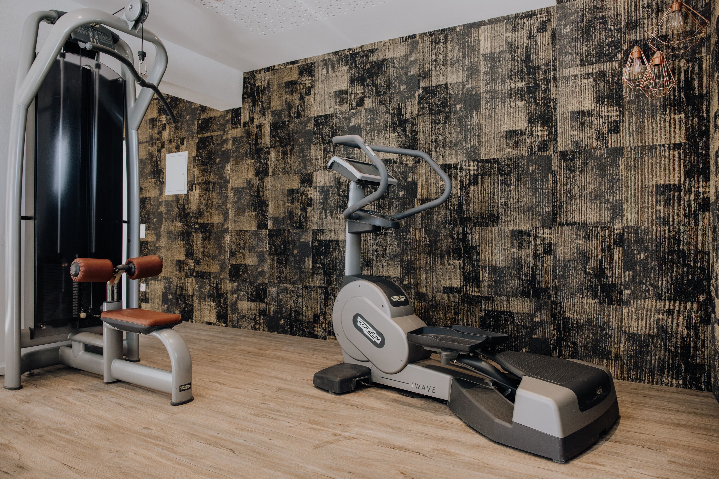 Un gimnasio con equipo de ejercicio, un espejo y un muro con diseño.