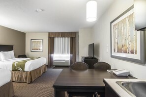A hotel room with a bed, a desk, a chair, a TV, a phone, and a window with curtains.