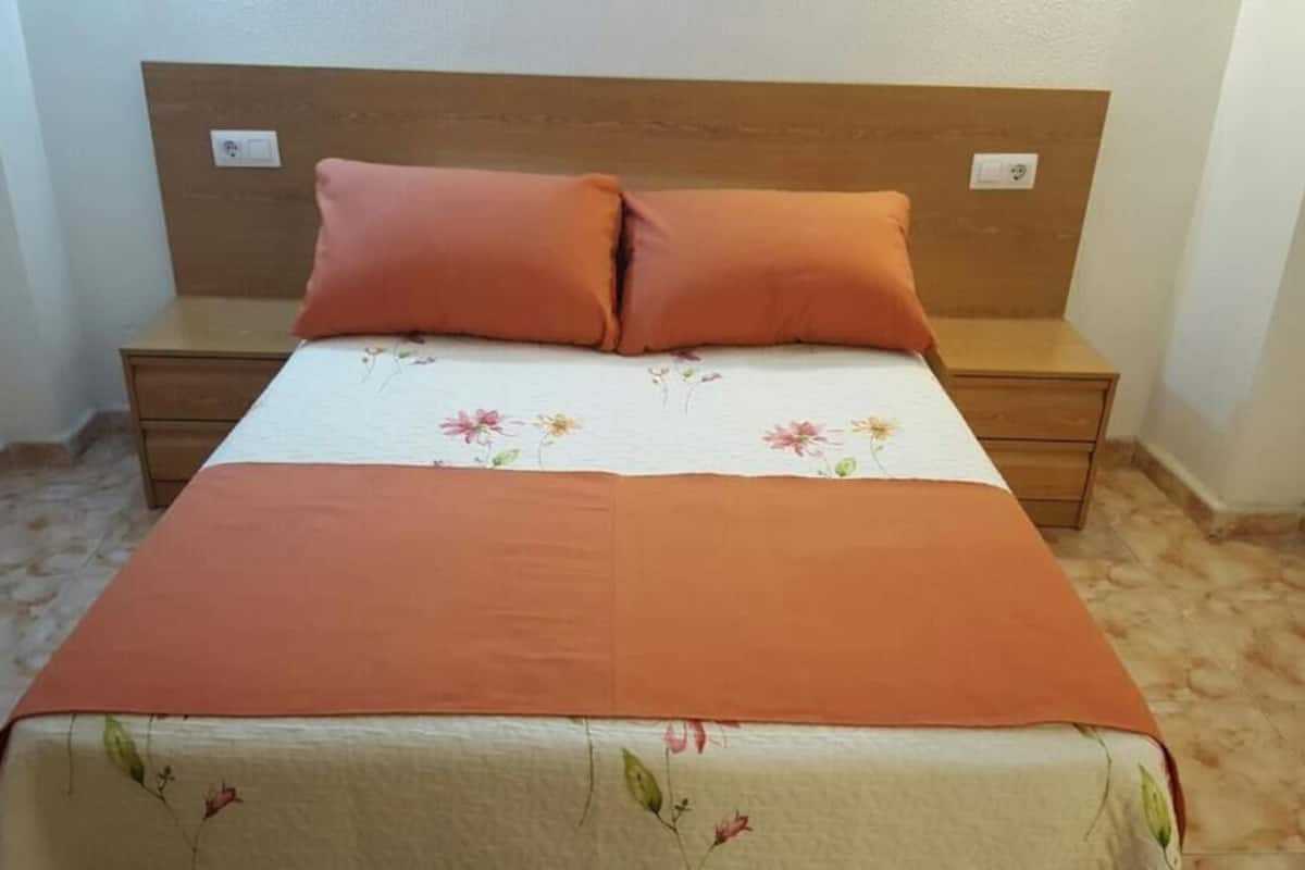 A bedroom with a bed, two nightstands, and a wooden headboard.