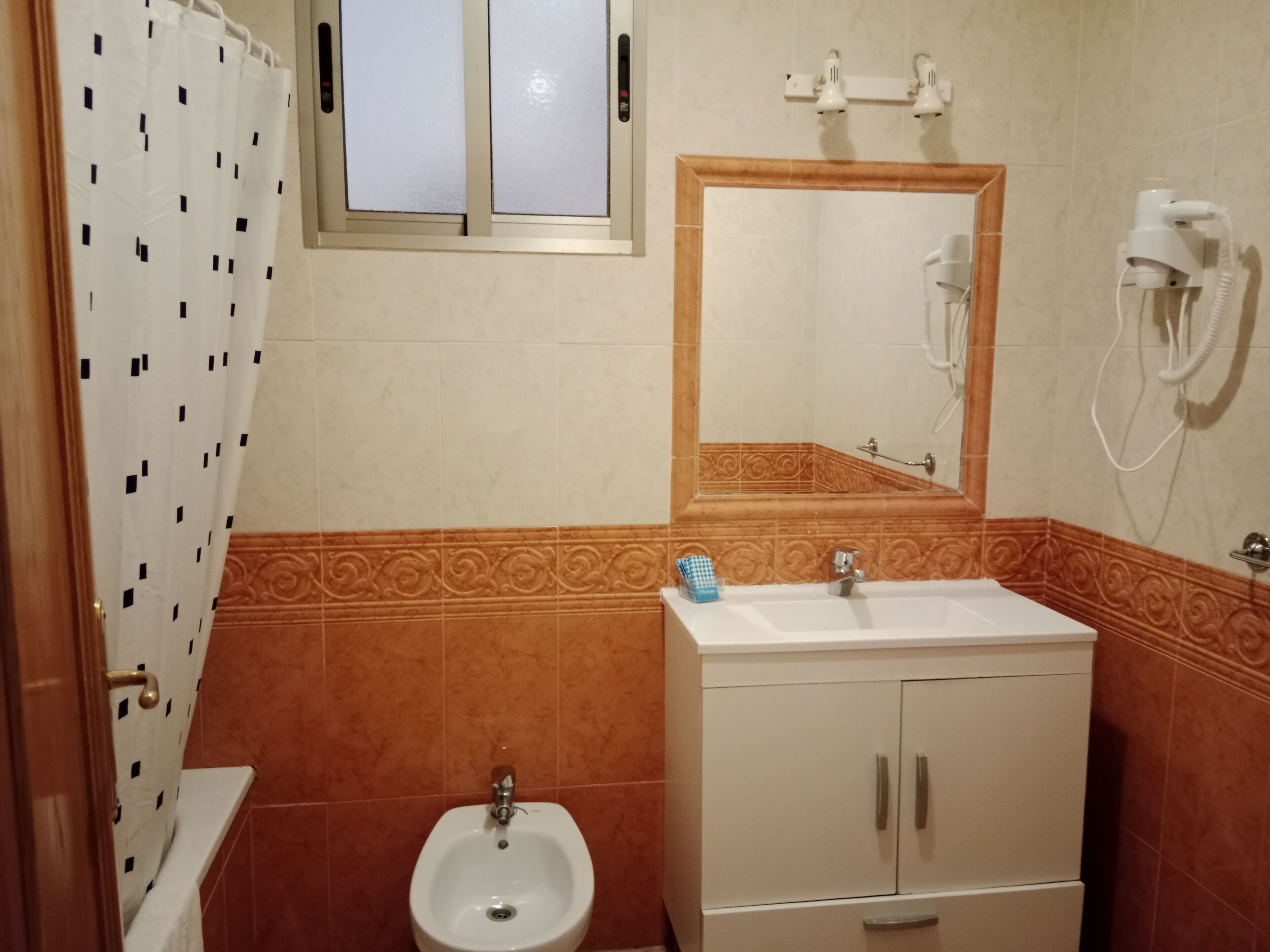 Un baño con bidé, lavamanos, espejo y toallero.