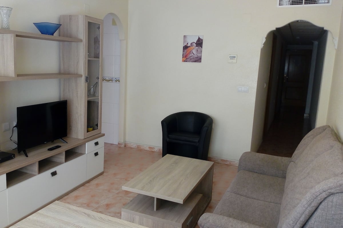 A living room with a TV, a black chair, a sofa, and a wooden coffee table.