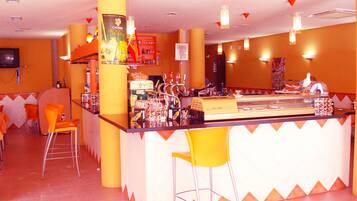 Zona de bar con mostrador, taburetes y diversas botellas y vasos.