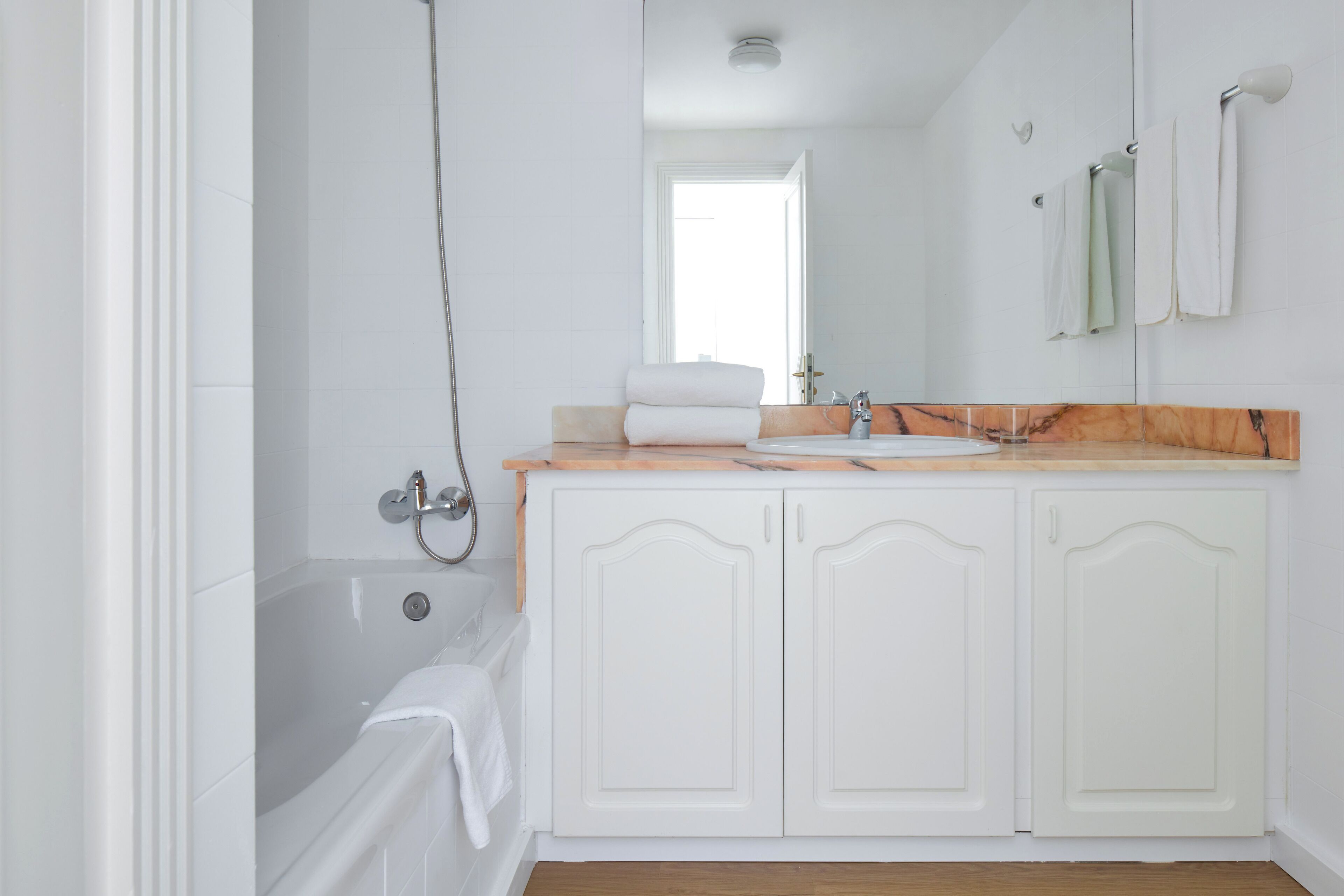 A bathroom with a bathtub, a sink, and a mirror.