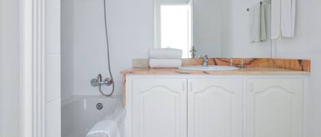 A bathroom with a bathtub, a sink, and a mirror.