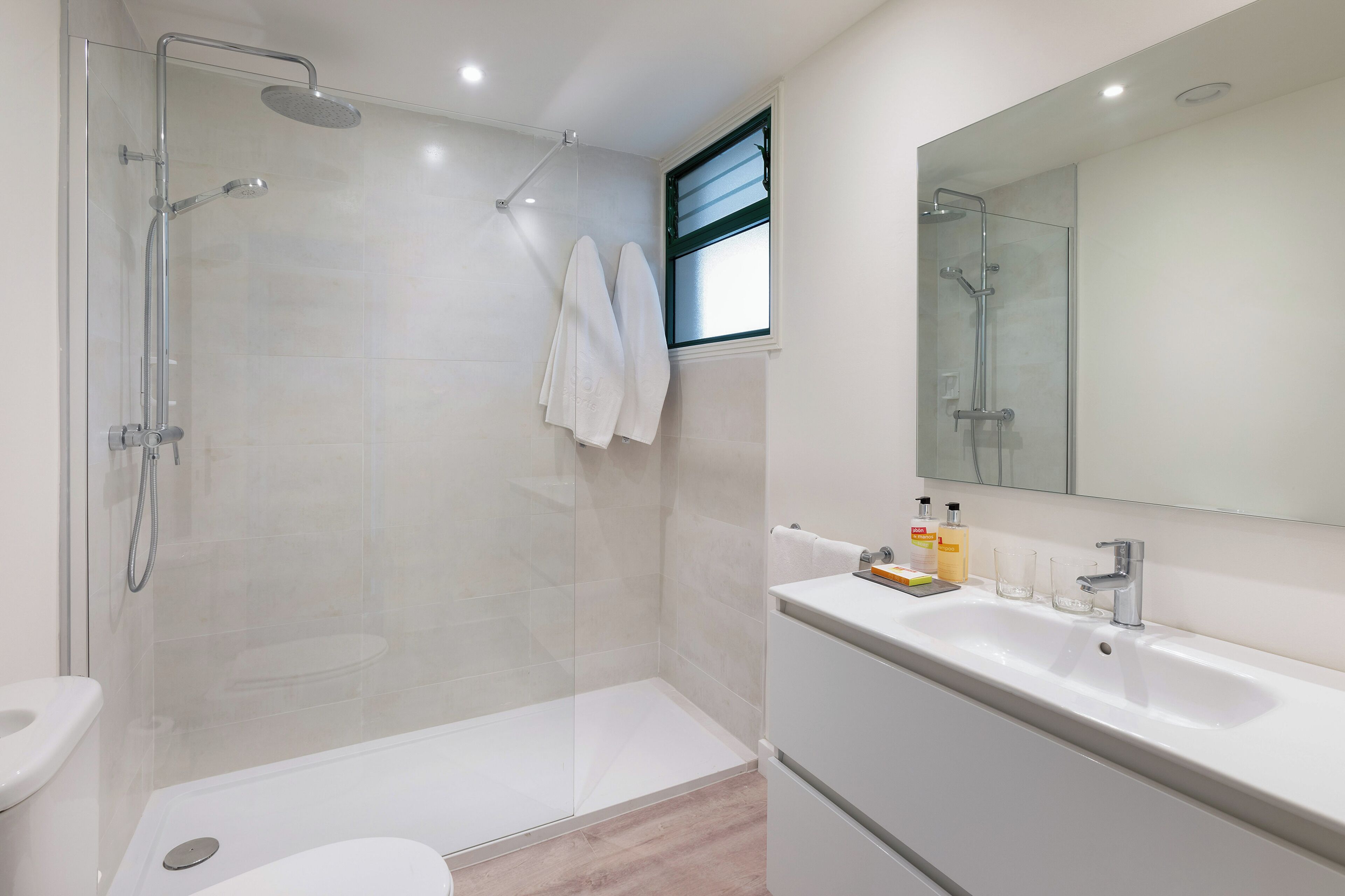 Une salle de bain moderne avec une douche à parois de verre, un lavabo blanc et un grand miroir.
