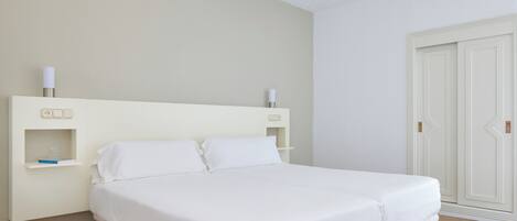 A bedroom with a bed, bedside tables, and a wardrobe.