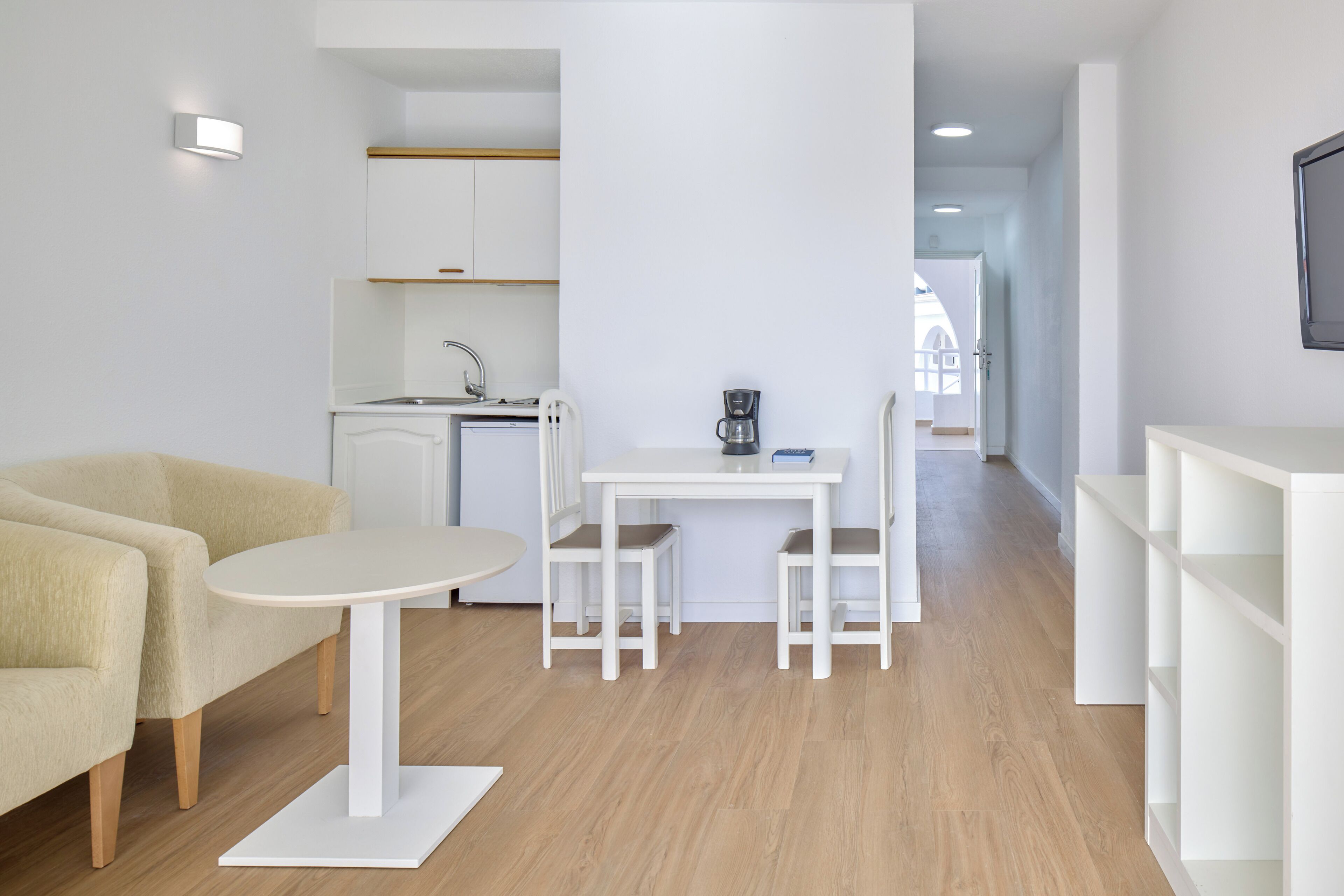 A modern, minimalist living space with a kitchen, dining area, and seating.